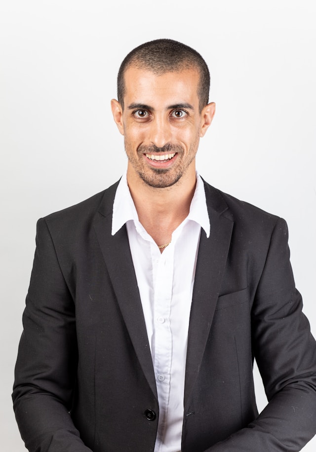smiling man in a business suit, but no tie, against a plain white background