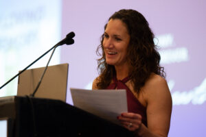 Woman with curly hair standing at a podium